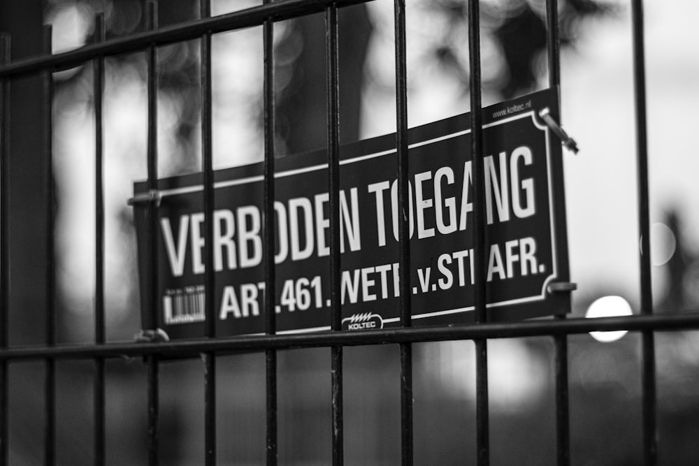 a black and white photo of a sign on a fence
