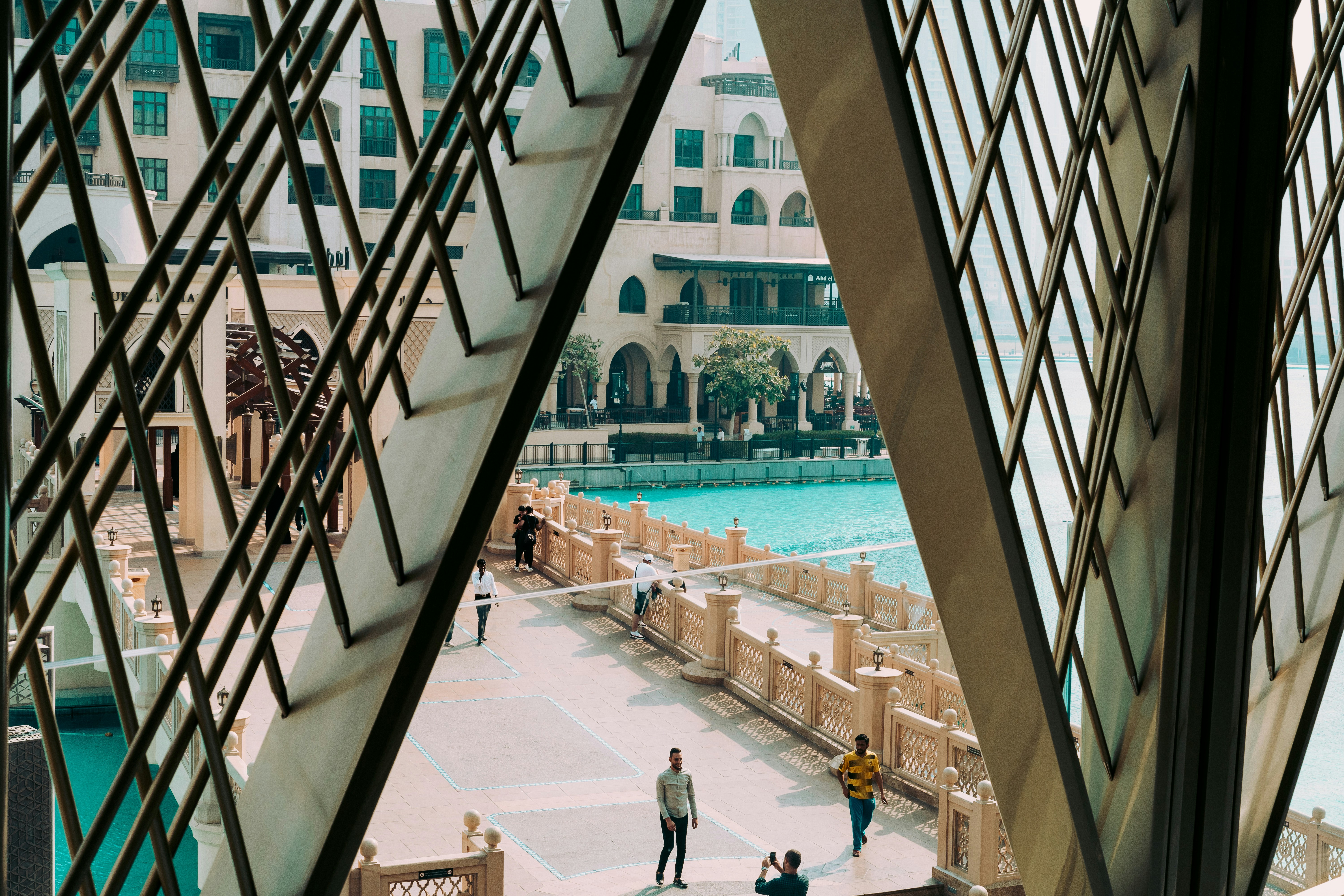 people walking on bridge beside pool in front of building, 