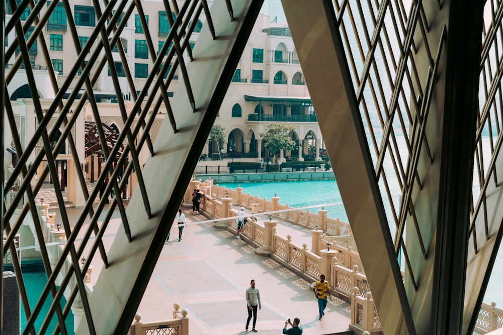 people walking on bridge beside pool in front of building