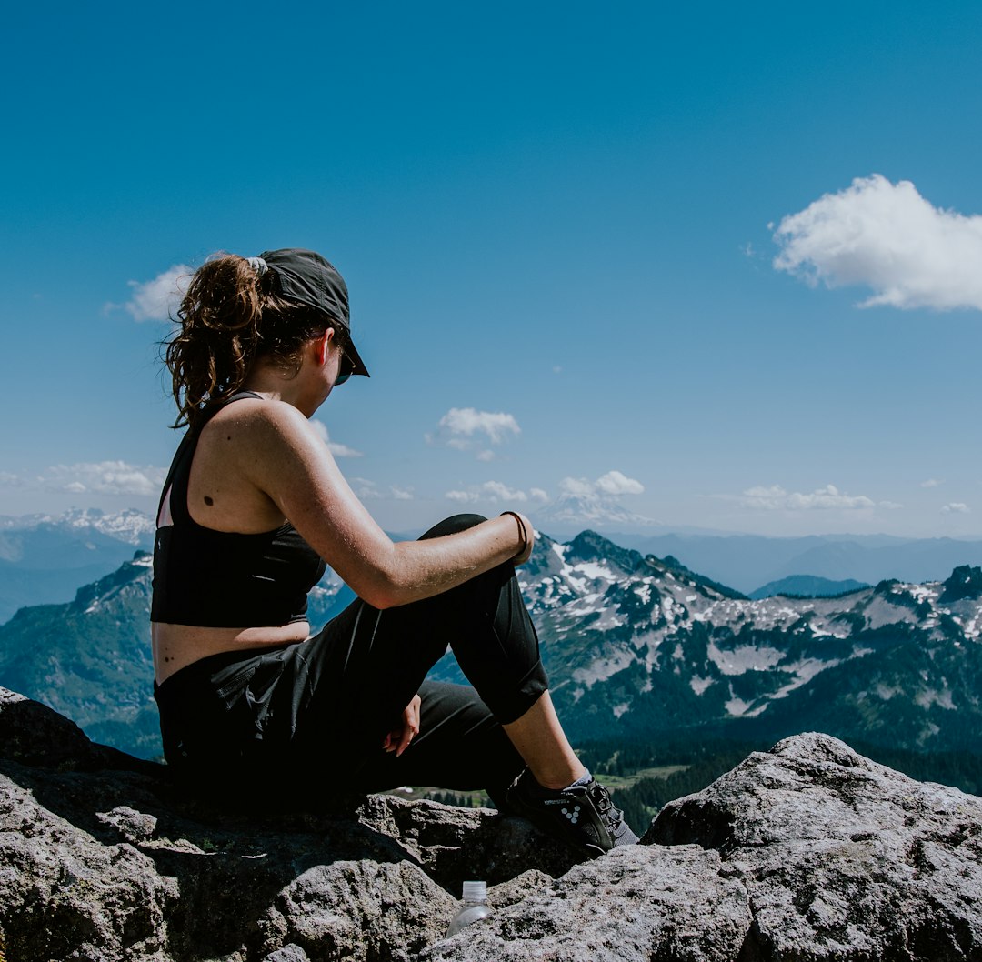 woman in black sports bra sitting on rock formation