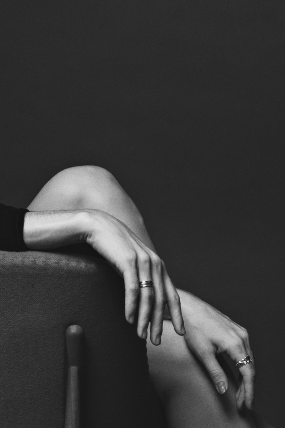 Photographie en niveaux de gris d’une personne assise portant des bagues à deux mains