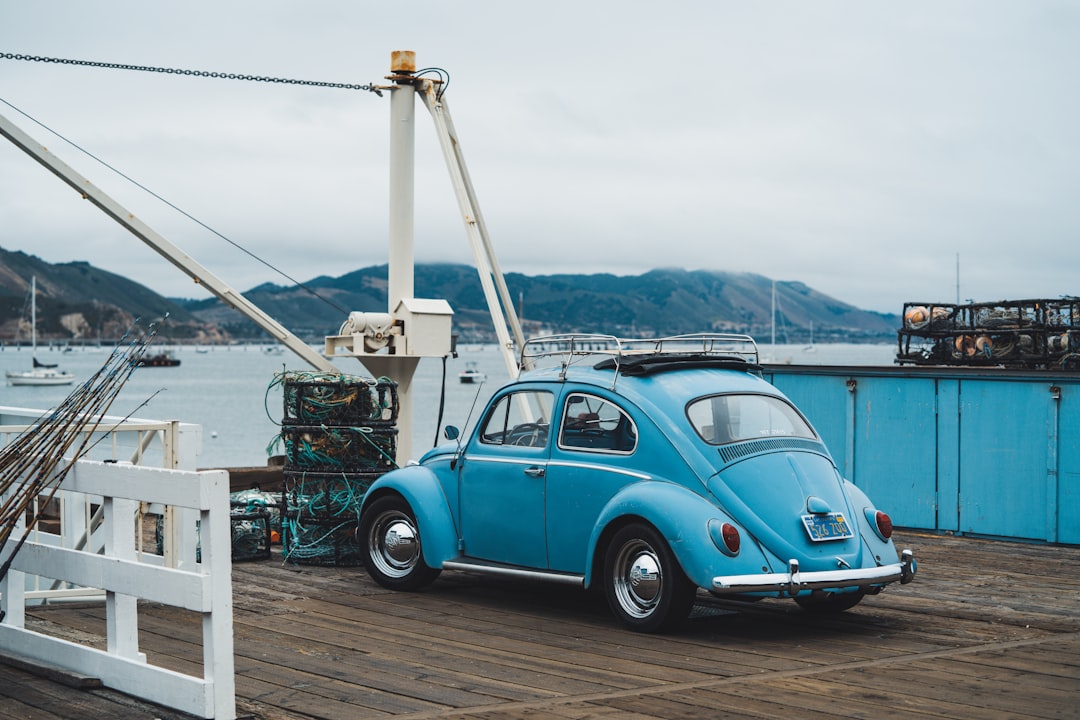 teal Volkswagen Beetle parked on wooden pavement