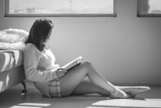 woman reading book sitting on floor beside furniture