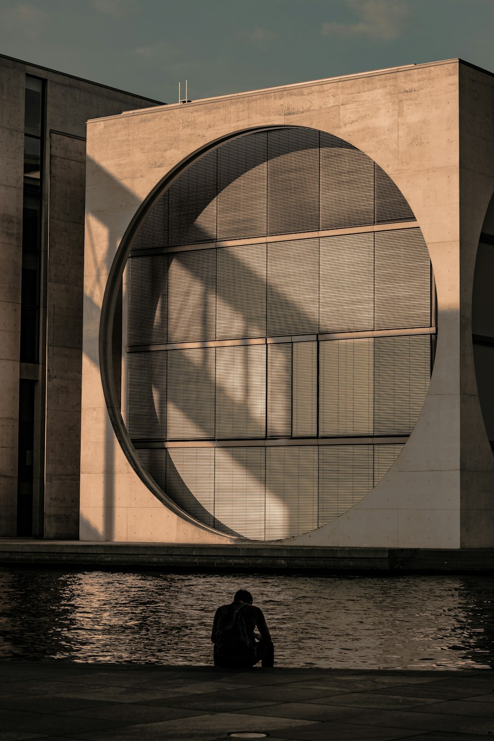 man sitting in front of water and building