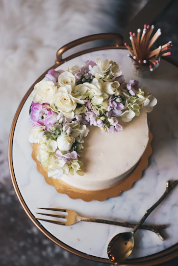 Close-up of an elegant pink and gold decorated cake with delicate floral accents on a white marble table.