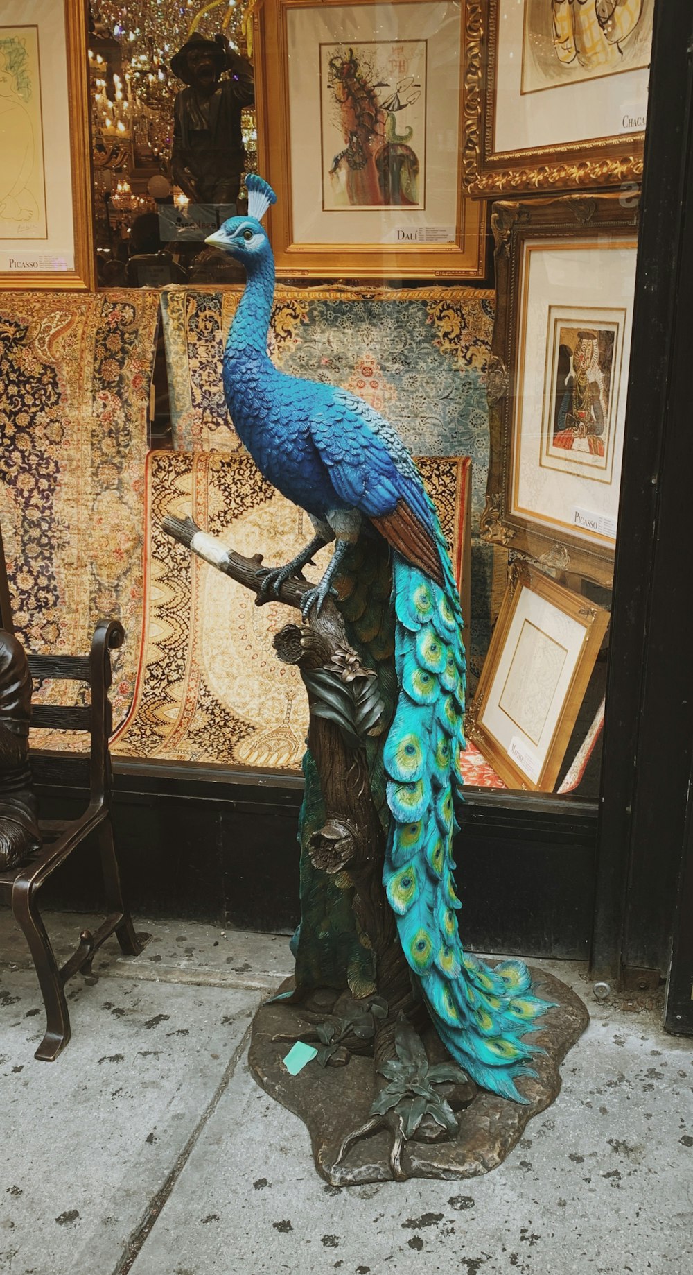 blue and green peacock statue on tree branch in room