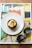A cupcake with creamy frosting sits on a white plate, which is placed on a magazine titled 'frieze'. Sunglasses rest beside the plate, adding a casual and stylish touch to the composition. The magazine's cover features an abstract artwork with geometric patterns and vibrant colors.
