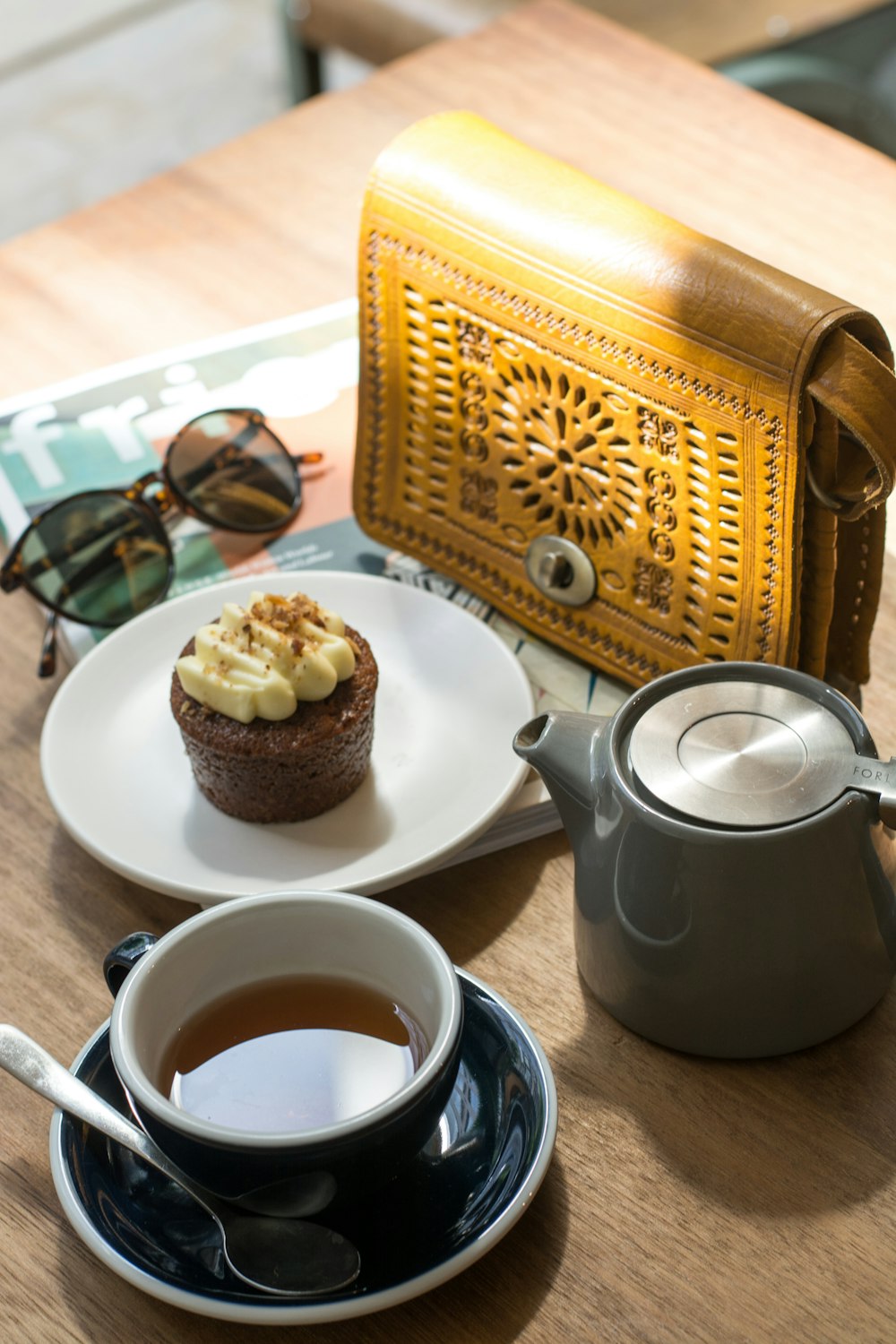 black teacup with tea beside cupcake