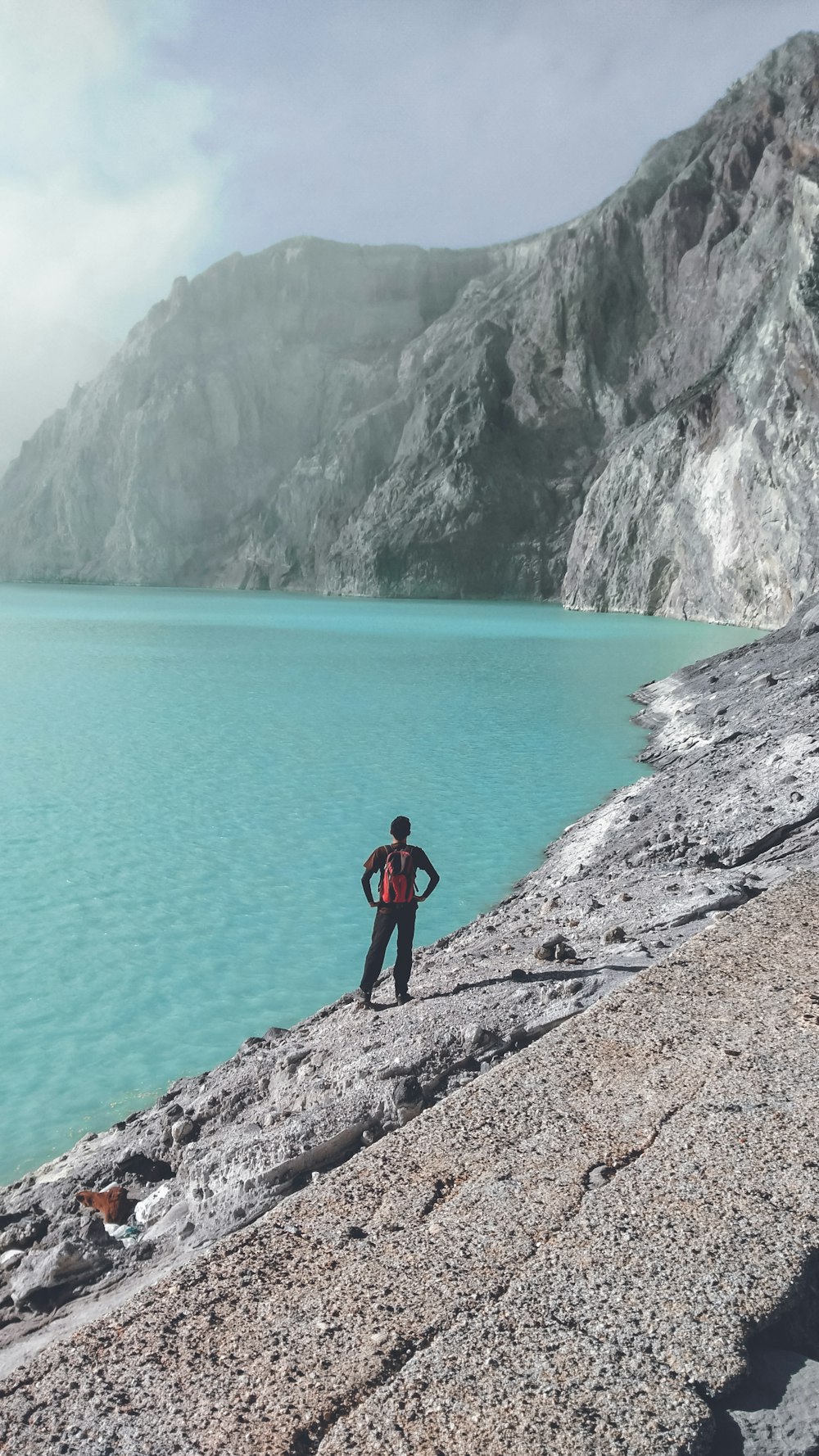 person standing near body of water and cliff during daytime