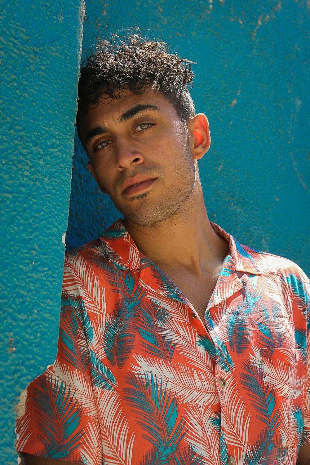 man leaning on teal wall