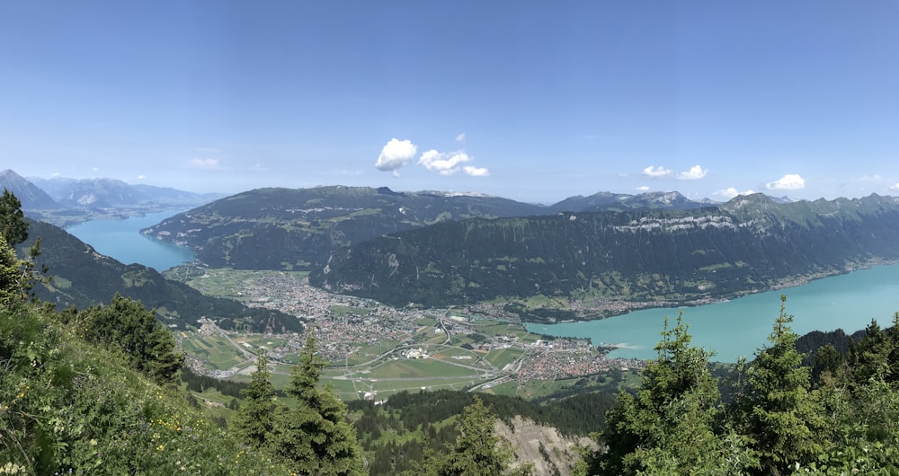 Häuser in der Nähe der grünen Wiese mit Blick auf Meer und Berge unter blauem und weißem Himmel