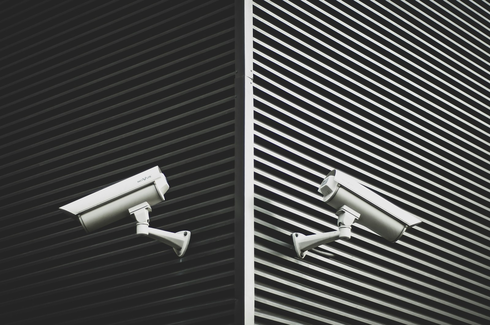 Two grey closed-circuit cameras mounted on a wall
