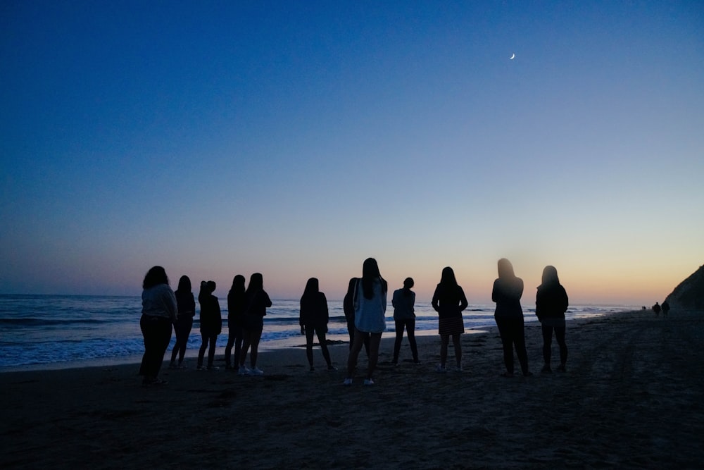 people standing beside sea during nighttime