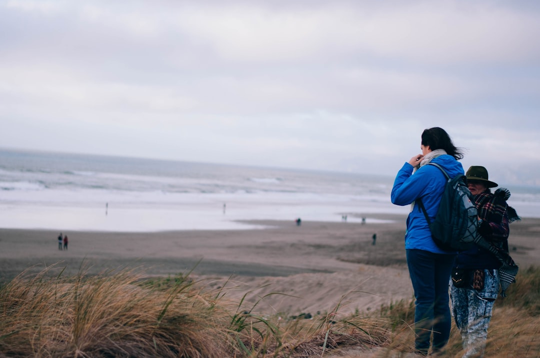 two person standing near green field viewing sea