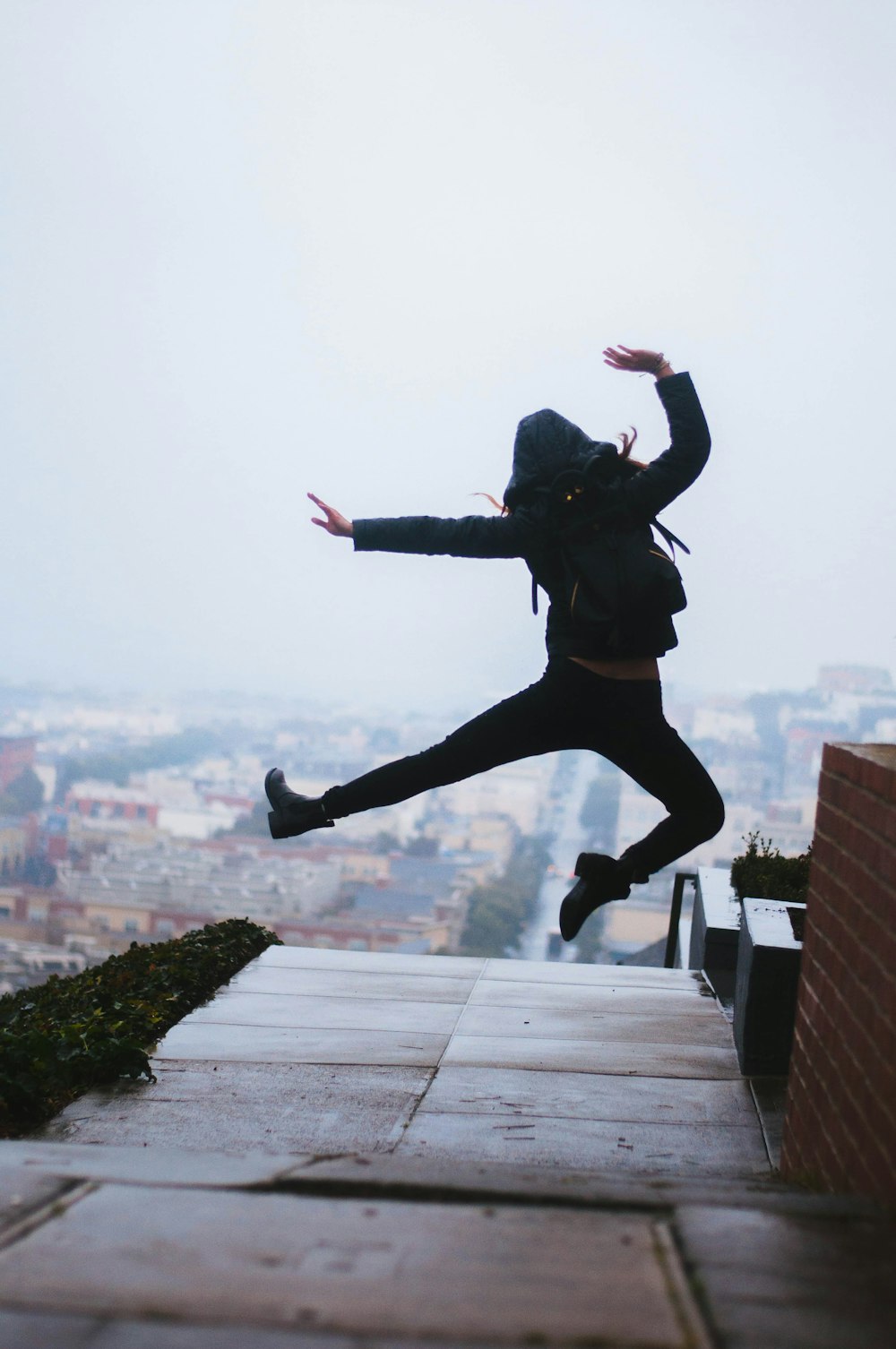 woman jump beside brown wall