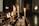 A series of lit candles placed on a decorative stand, surrounded by melted wax. The setting appears dimly lit, likely a religious or contemplative space.