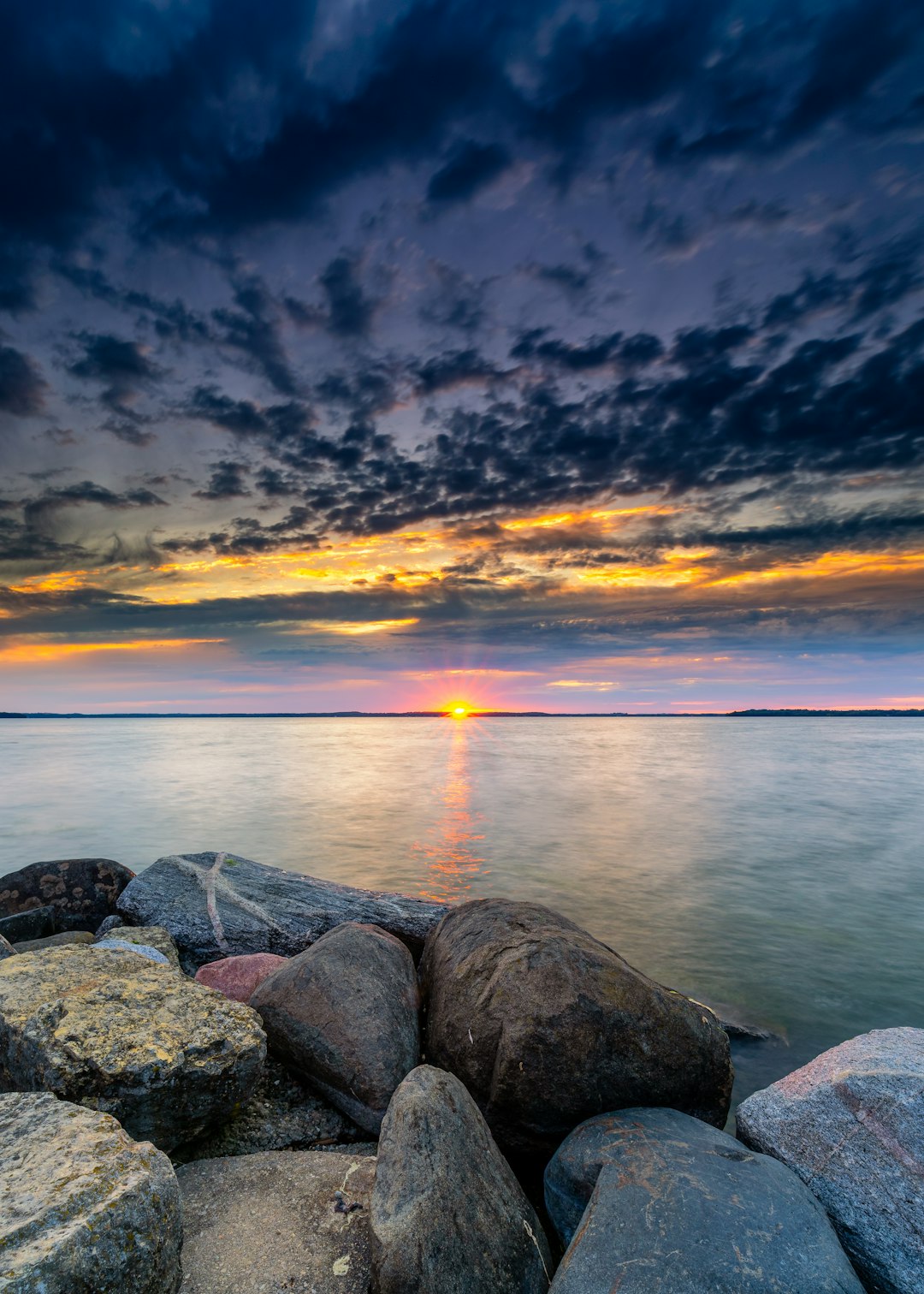 gray and black rocks beside body of water at golden hour