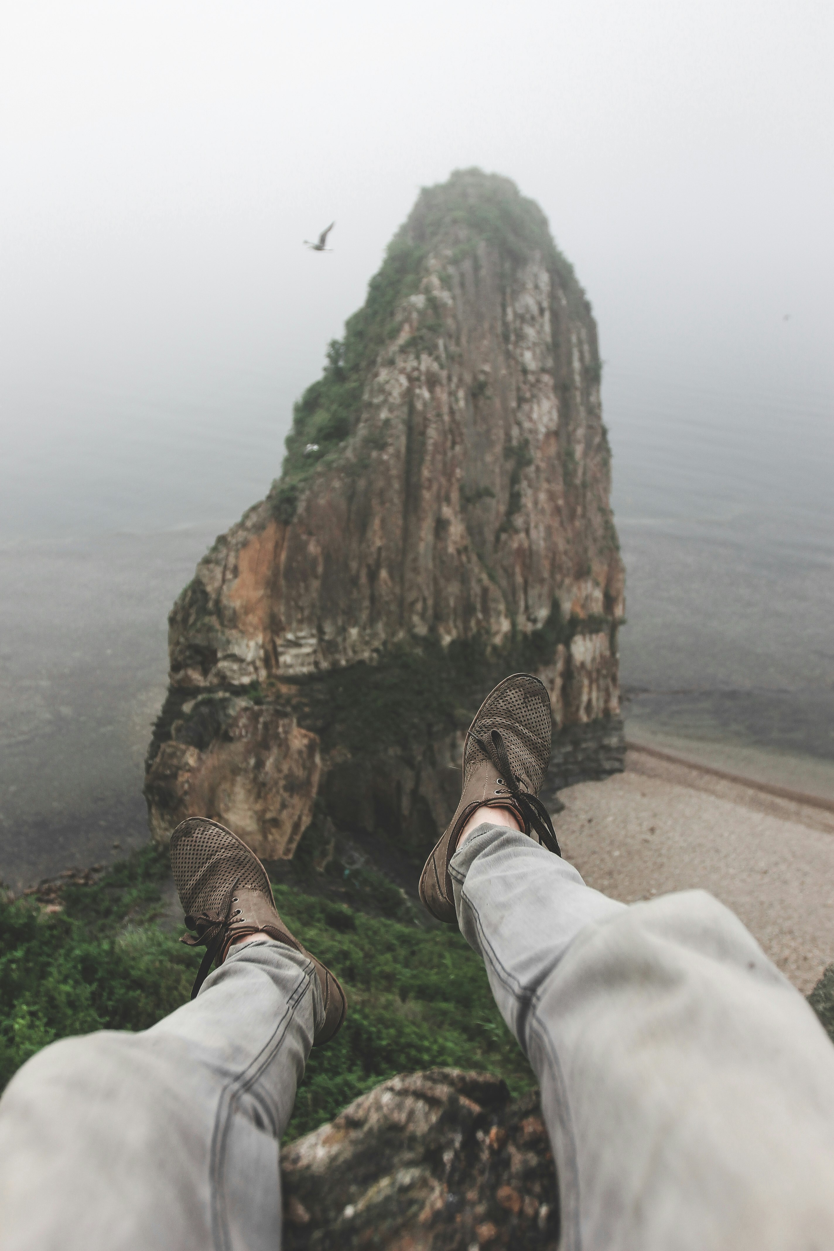 person sitting on cliff during daytime