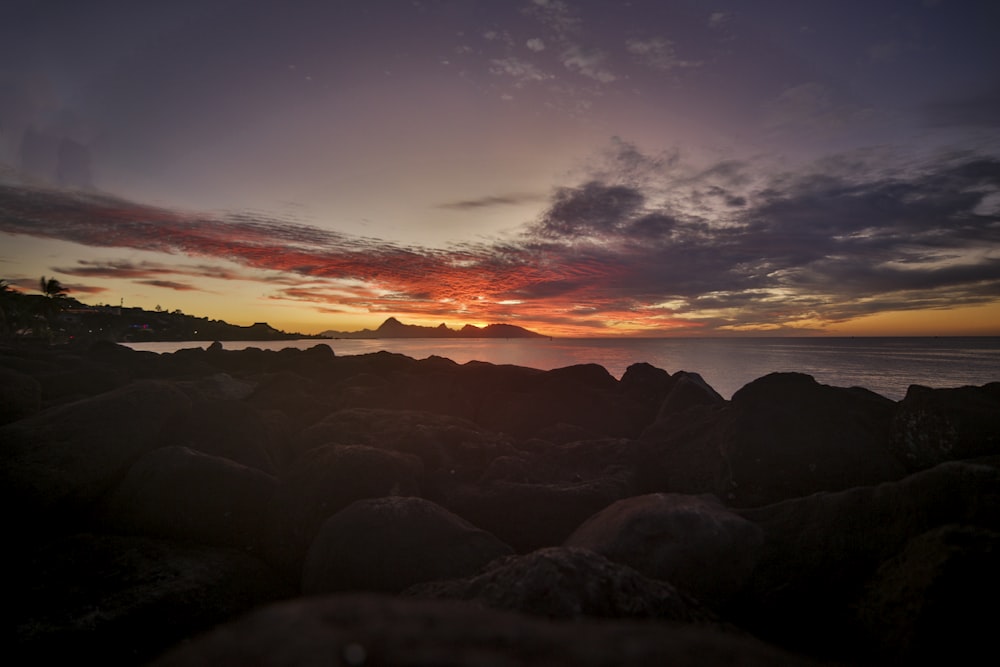 body of water across mountain during sunset