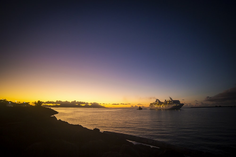 a cruise ship is in the distance as the sun sets