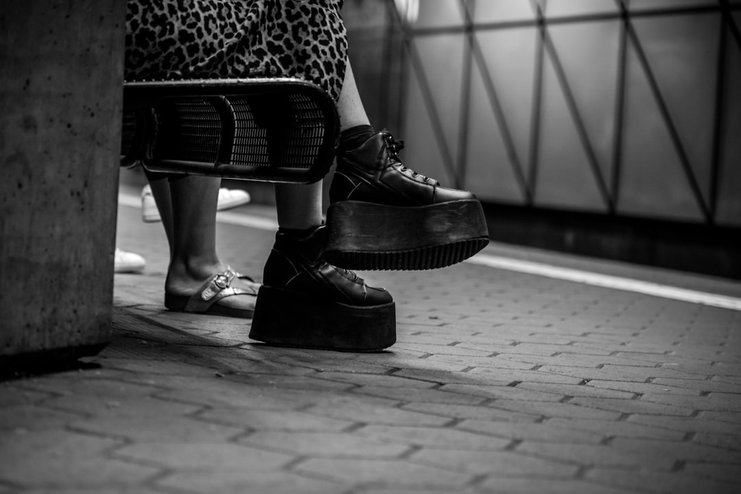 grayscale photo of person wearing black wedges shoes