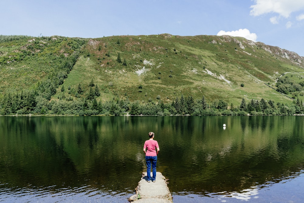 person in pink shirt standing on rock