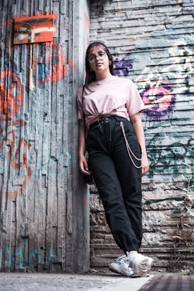 Young people wearing streetwear clothes in an urban setting with graffiti walls.