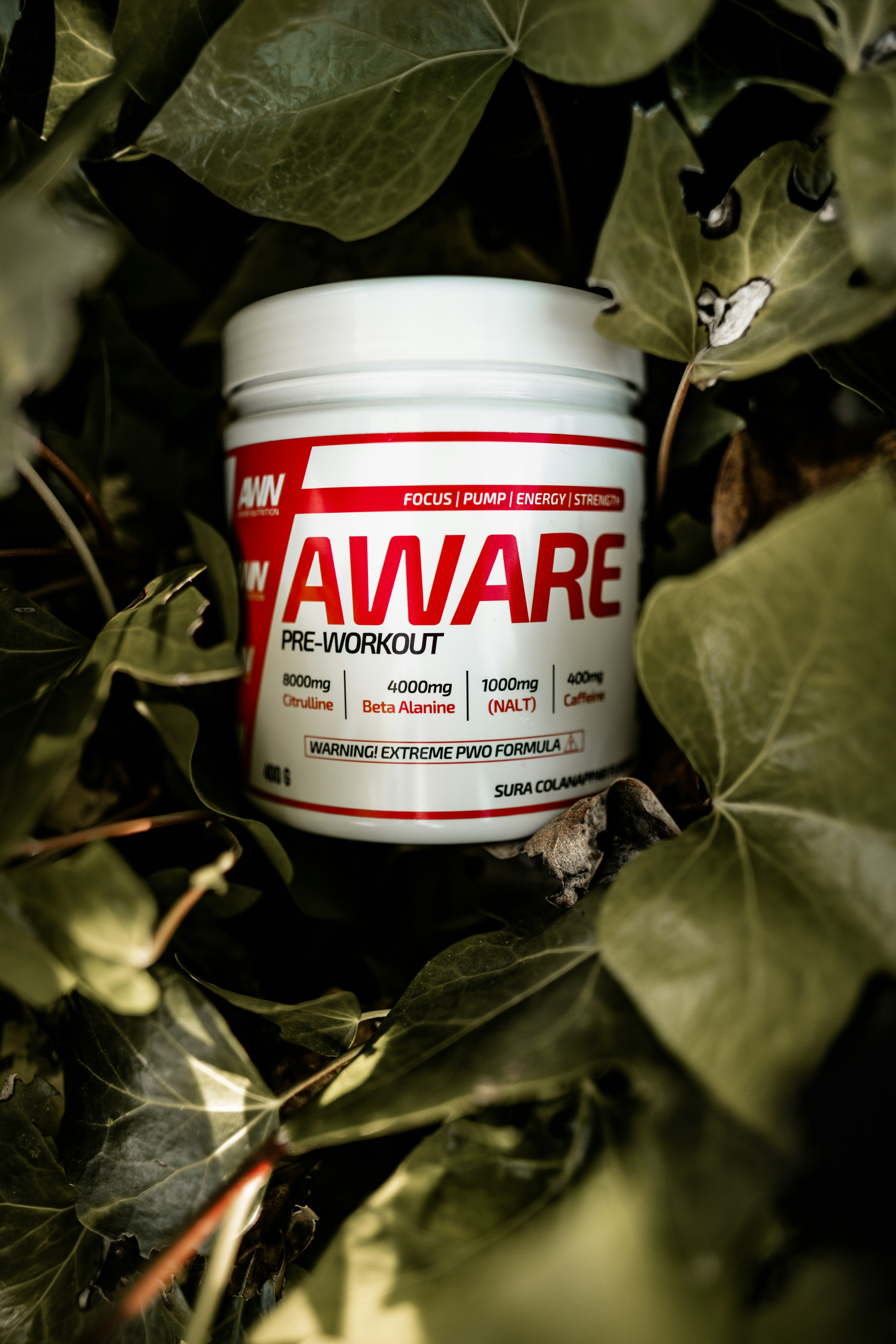 Red and black pre-workout supplement container on gym bench with weights in background