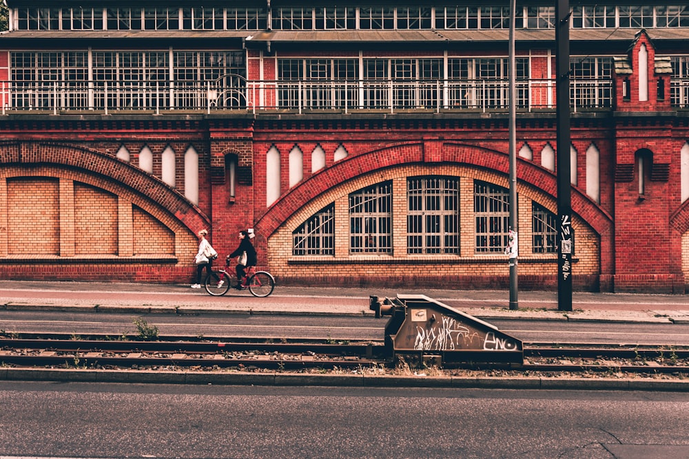 person riding bicycle near concrete building during daytime