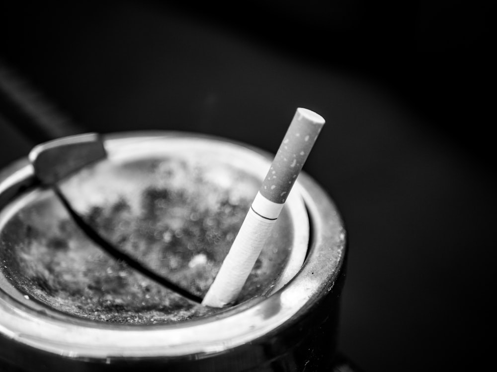 Foto en escala de grises de un palo de cigarrillo en el cenicero