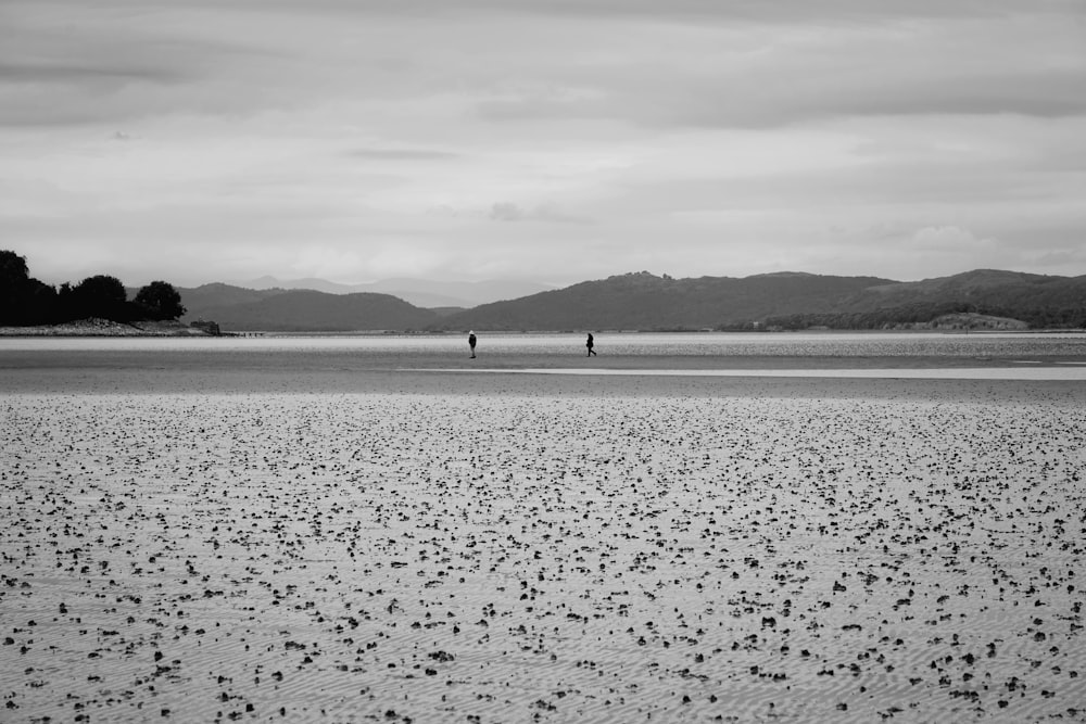 Una foto en blanco y negro de una persona caminando en una playa