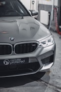 A sleek silver car with modern design featuring sharp headlights and a distinctive front grille. The branding 'nanolex protected' is visible on the front. The setting appears to be an indoor garage with tools and cables in the background.