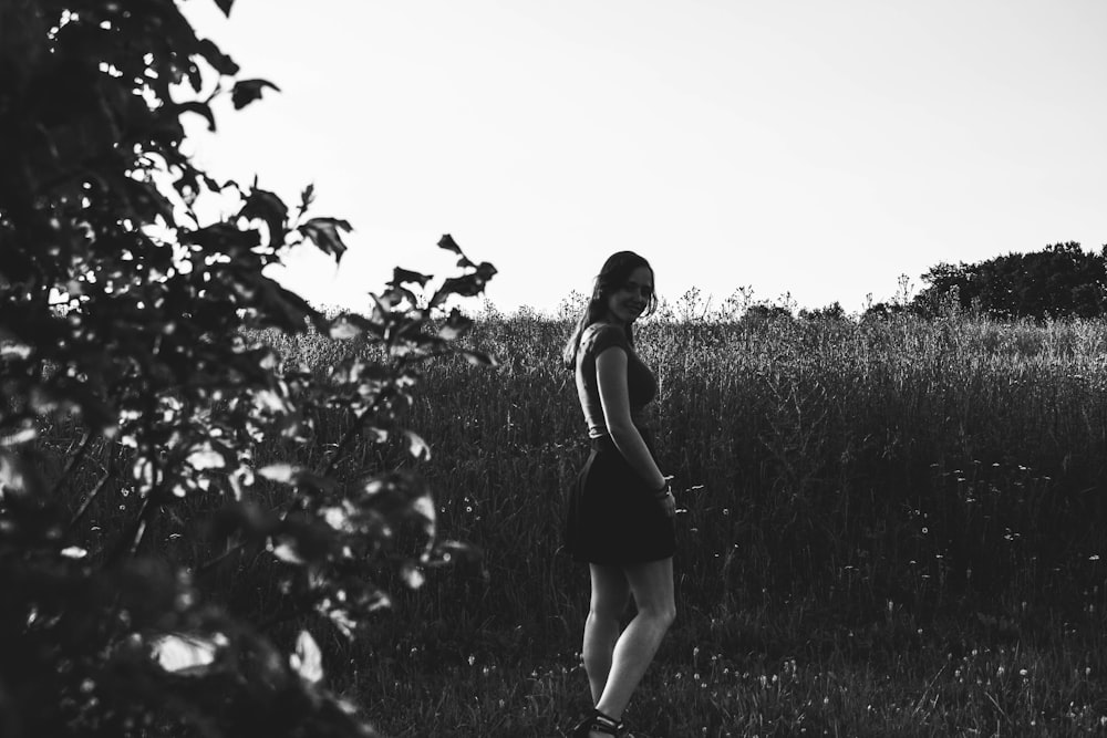 greyscale photo of woman standing on field