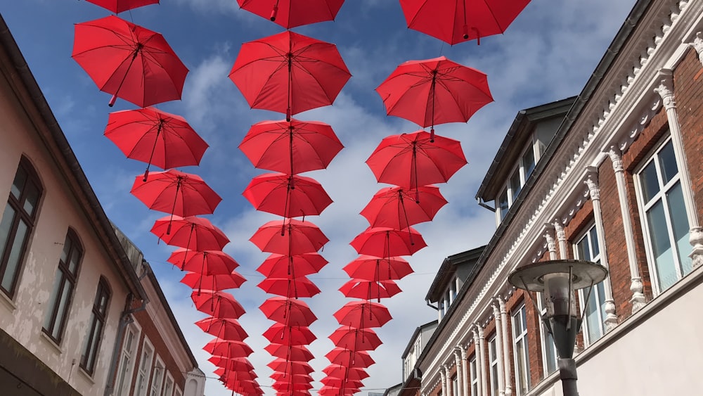 red umbrellas hanging on skies in between buildings