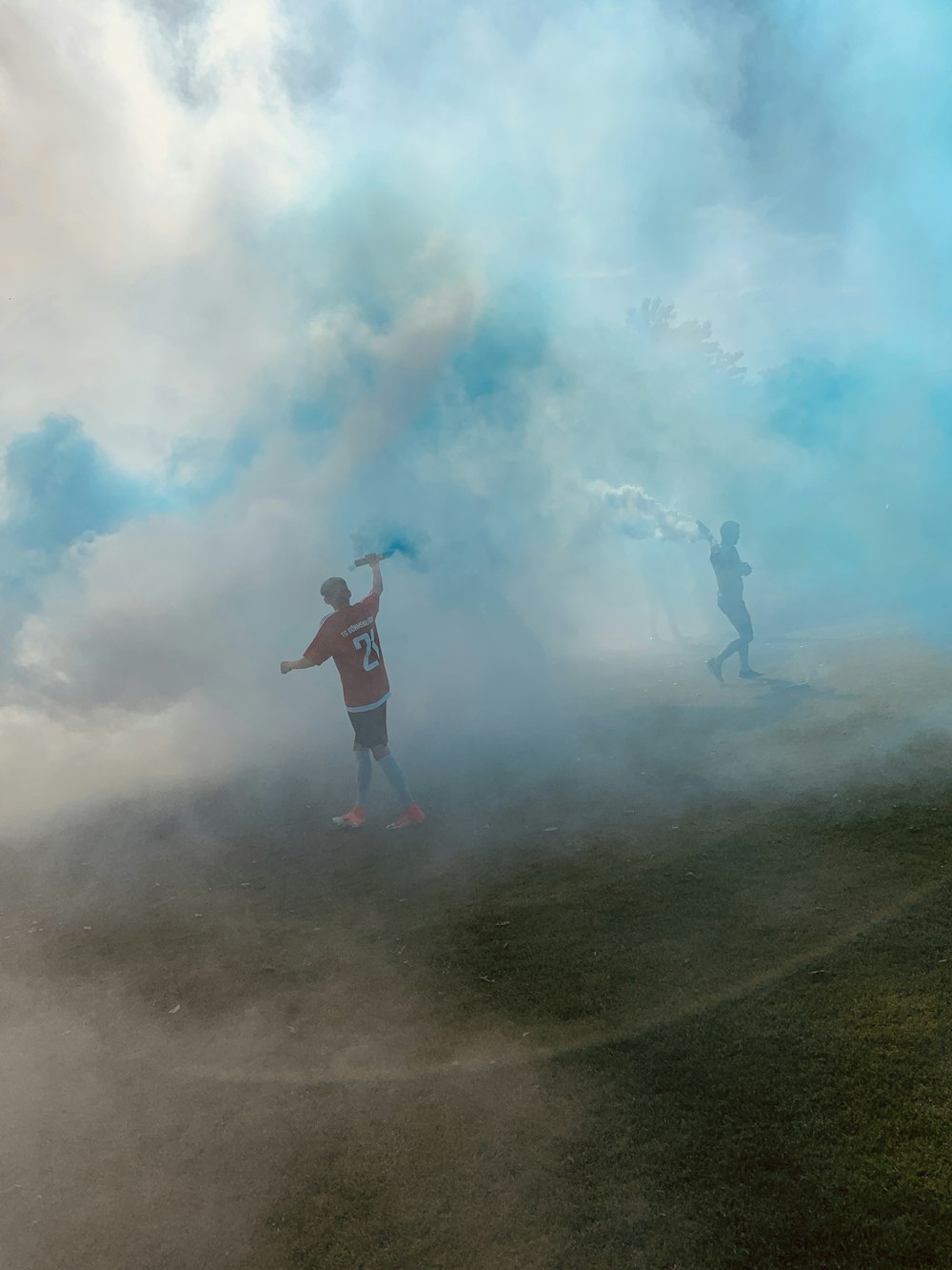 two people walking in circles holding smoke sticks