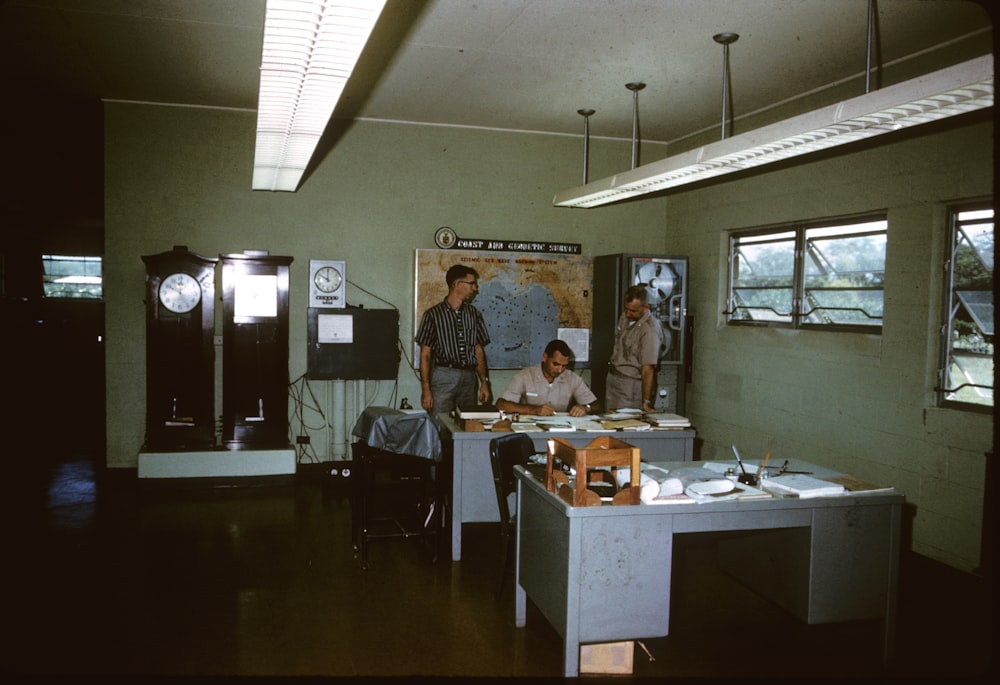 two men standing in between man sitting near table