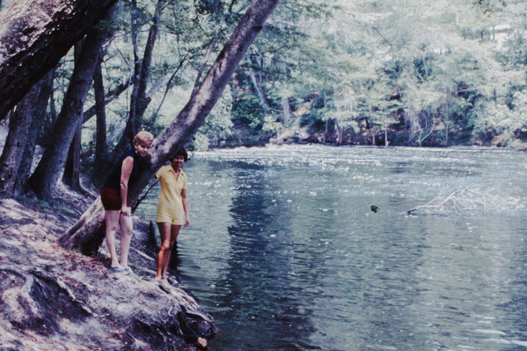 two persons holding on to three beside body of water