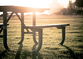 grey picnic table on grass field during sunset