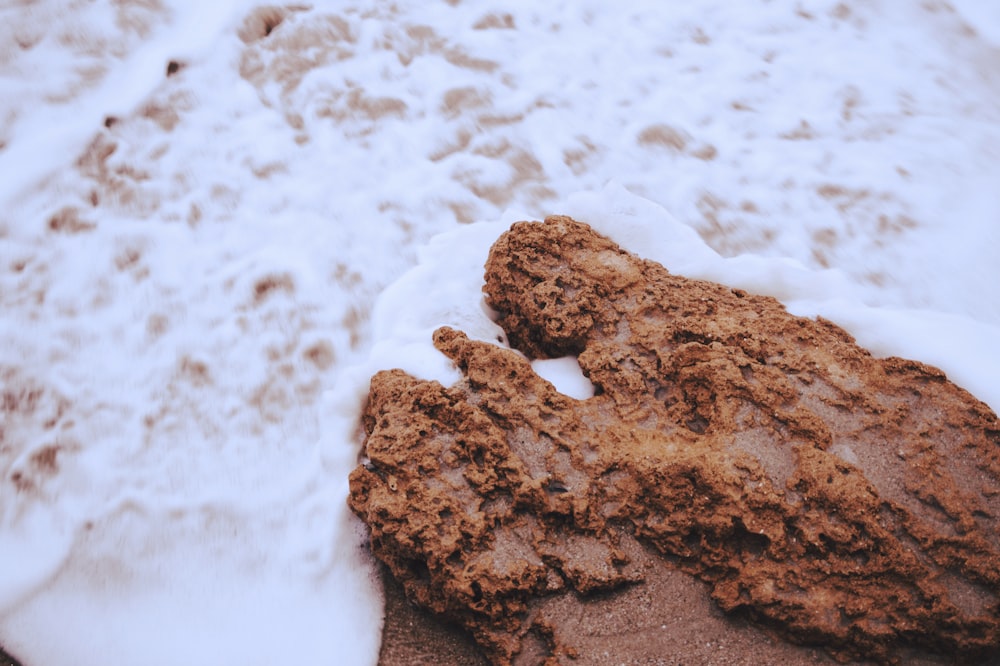 a rock covered in snow next to a body of water