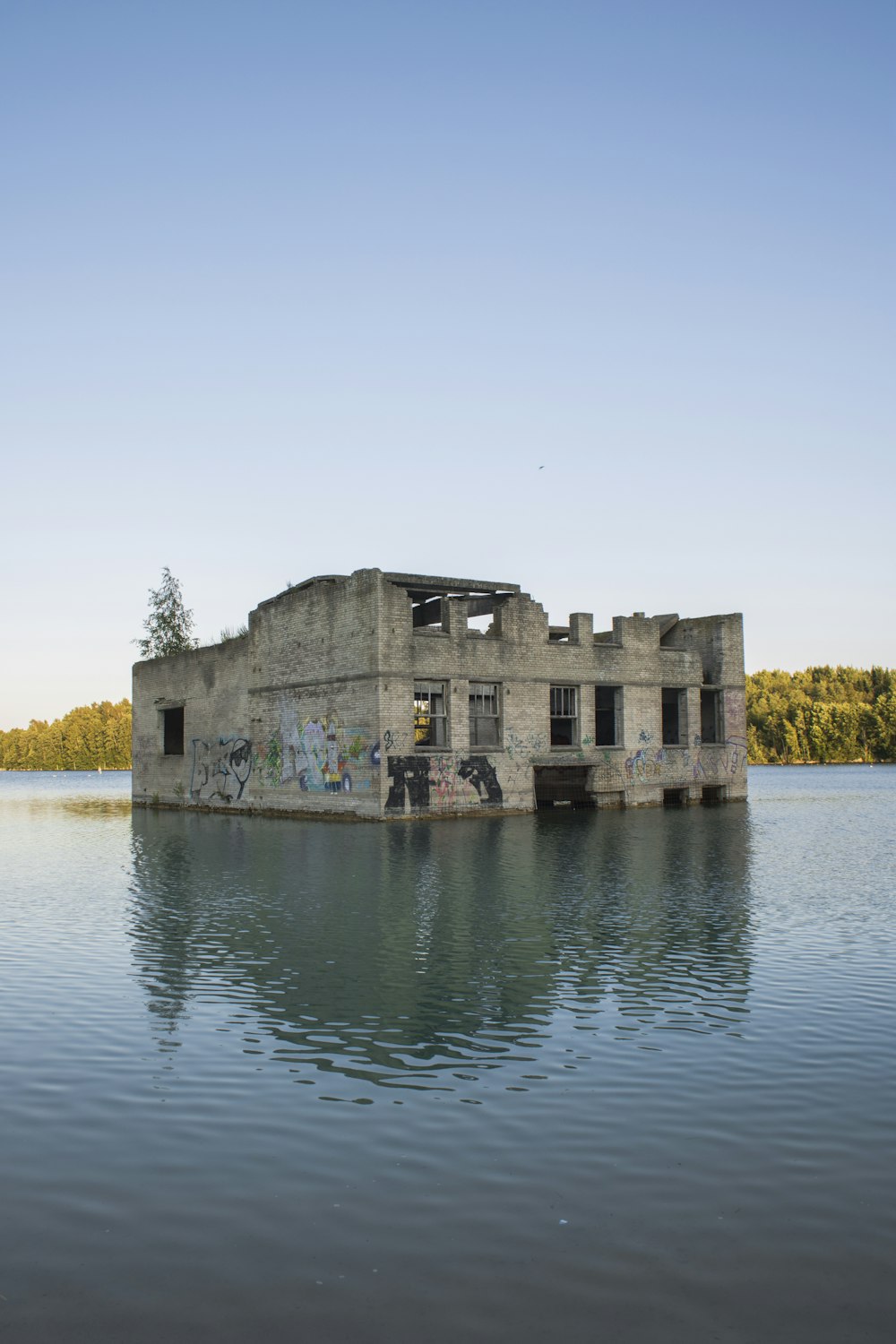 grey house ruins submerged in water under clear blue sky