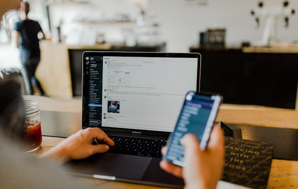 person using phone and laptop