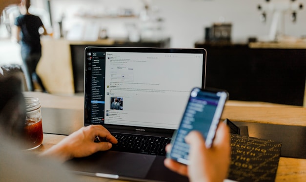 person using phone and laptop