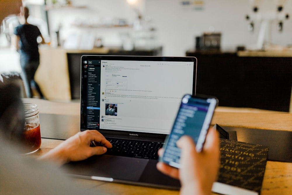 person using phone and laptop