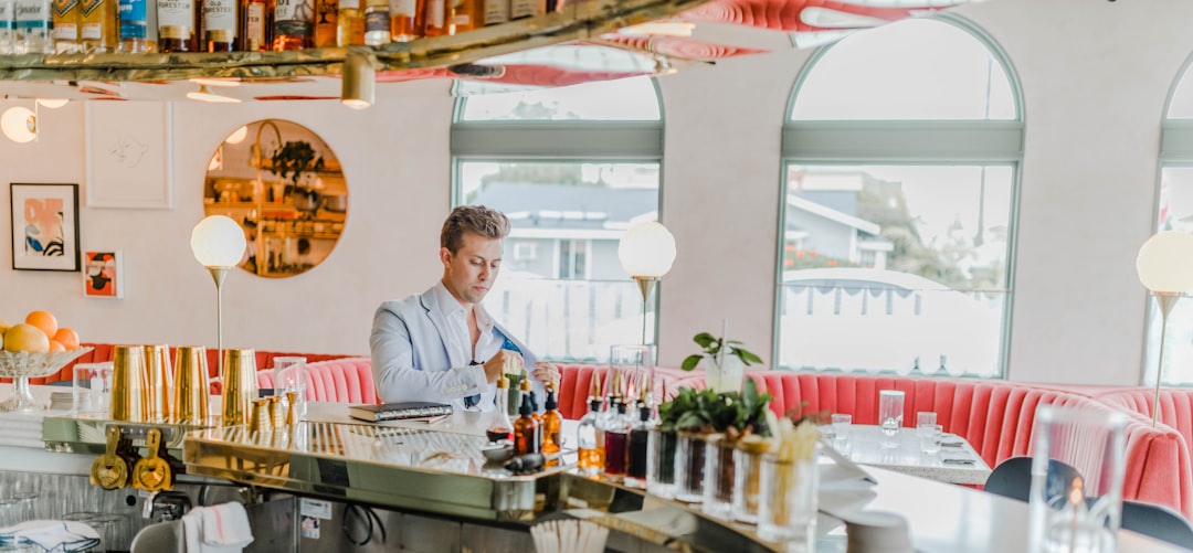 man wearing gray suit standing beside counter, Male model checkout out at a trendy bar in hotel drinking a cocktail.