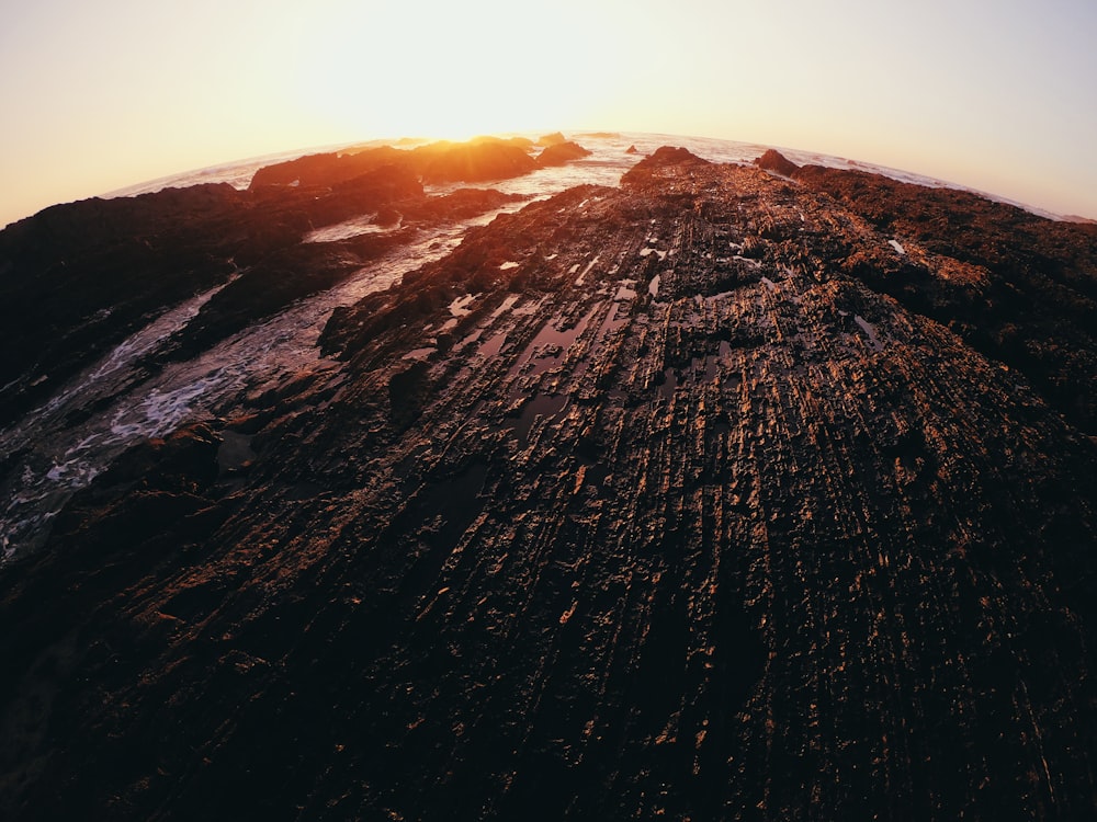 the sun is setting over a rocky mountain