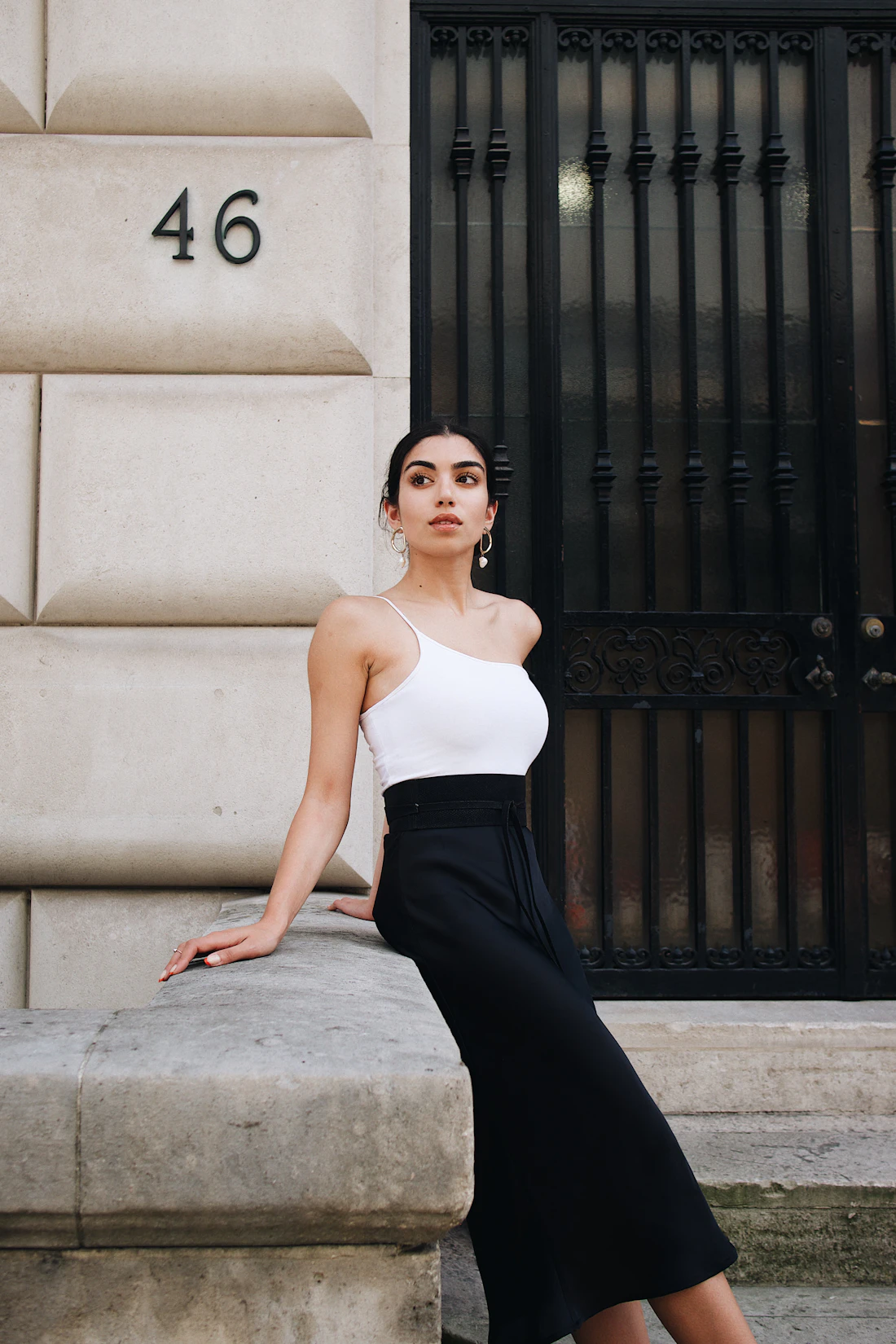 Model in a white camisole and dark skirt on a city street