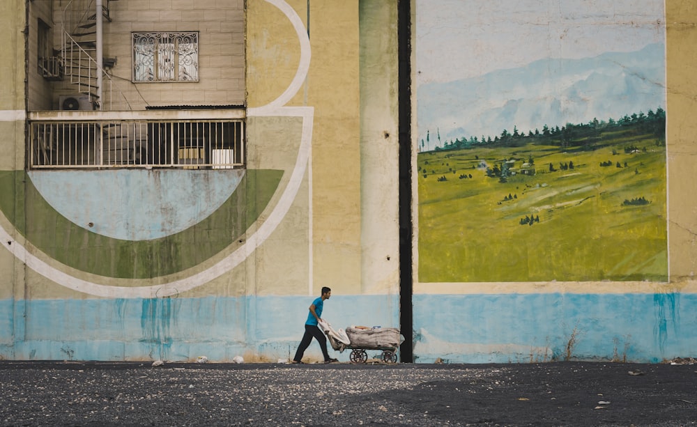 man pushing wheelbarrow near building