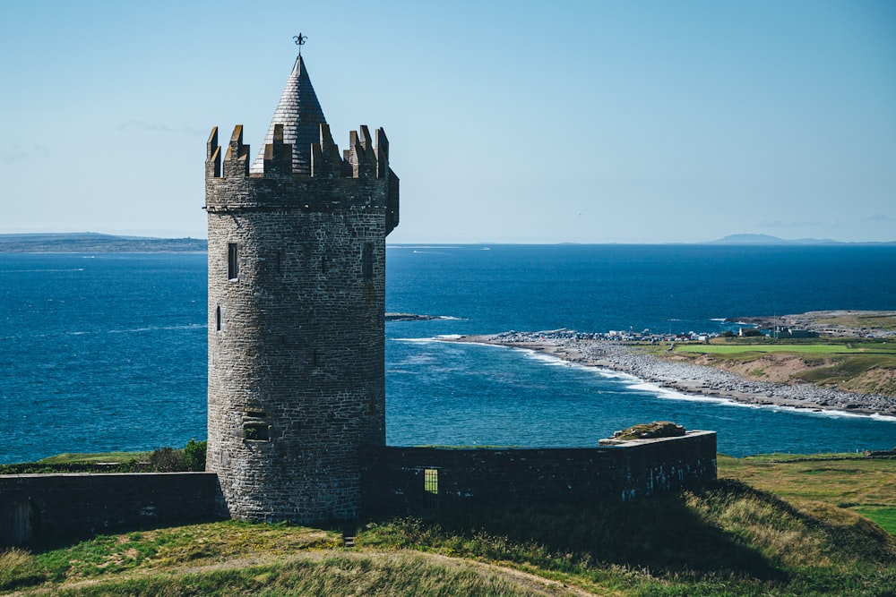 Torre cinzenta do castelo na costa da montanha durante o dia