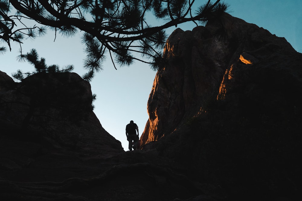 uomo in piedi accanto alle formazioni rocciose nere