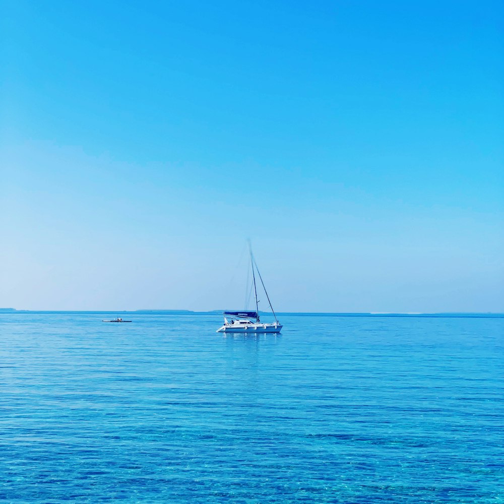 white and blue boat on body of water at daytime